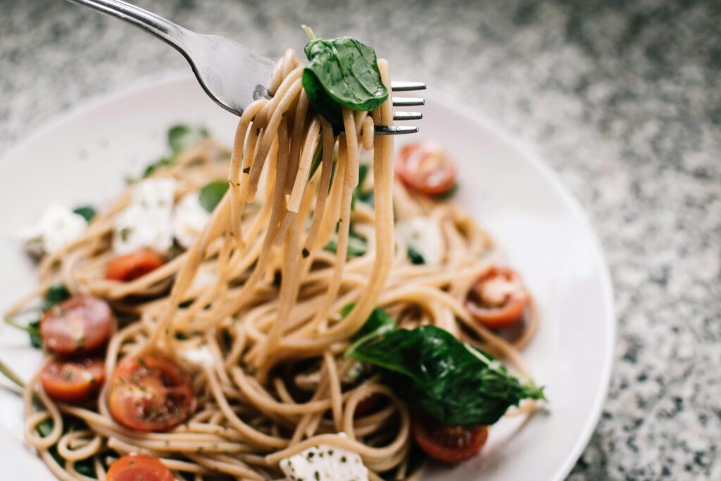 pexels photo 1279330 1279330 Delicious whole wheat pasta with fresh spinach, cherry tomatoes, and feta cheese in a close-up shot.