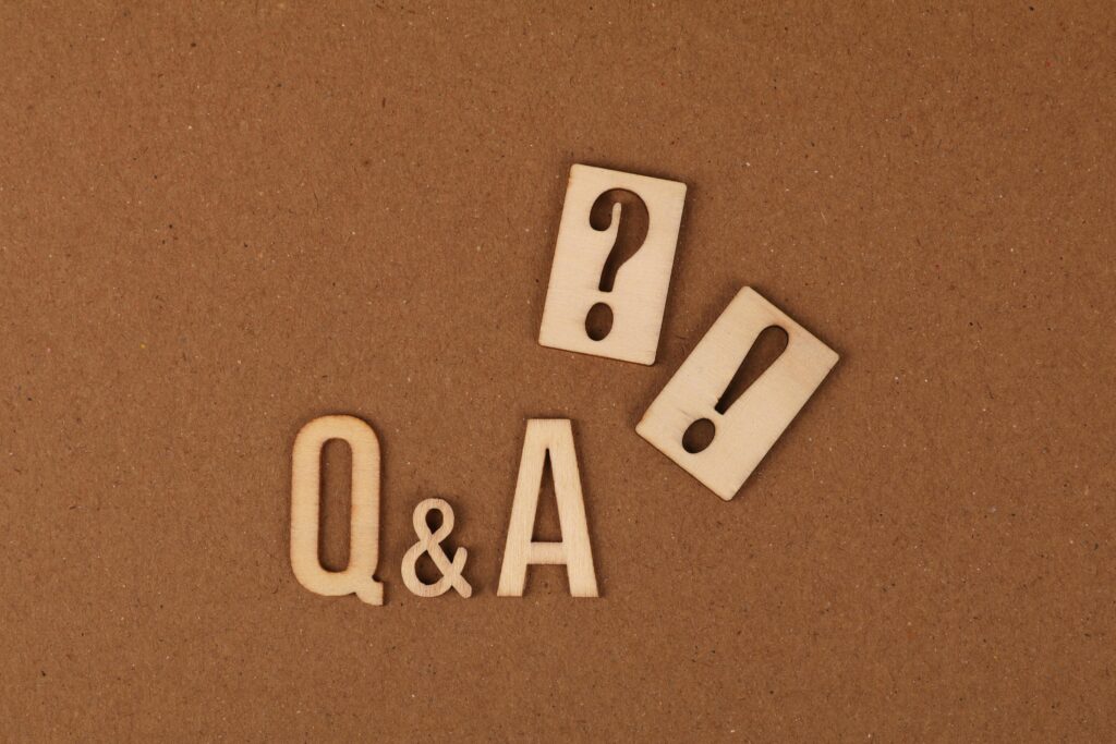 Wooden cutouts of Q&A with question and exclamation marks on a brown backdrop.