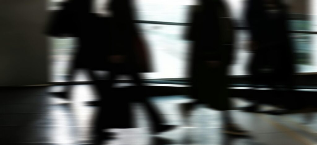 Abstract blurred motion of people walking indoors, depicting urban life and busy routines.
